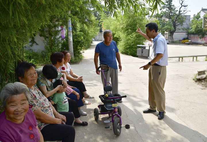 县翠峰镇上宝玉村,西安市工信局的退休干部李国平(右一)与村民聊天