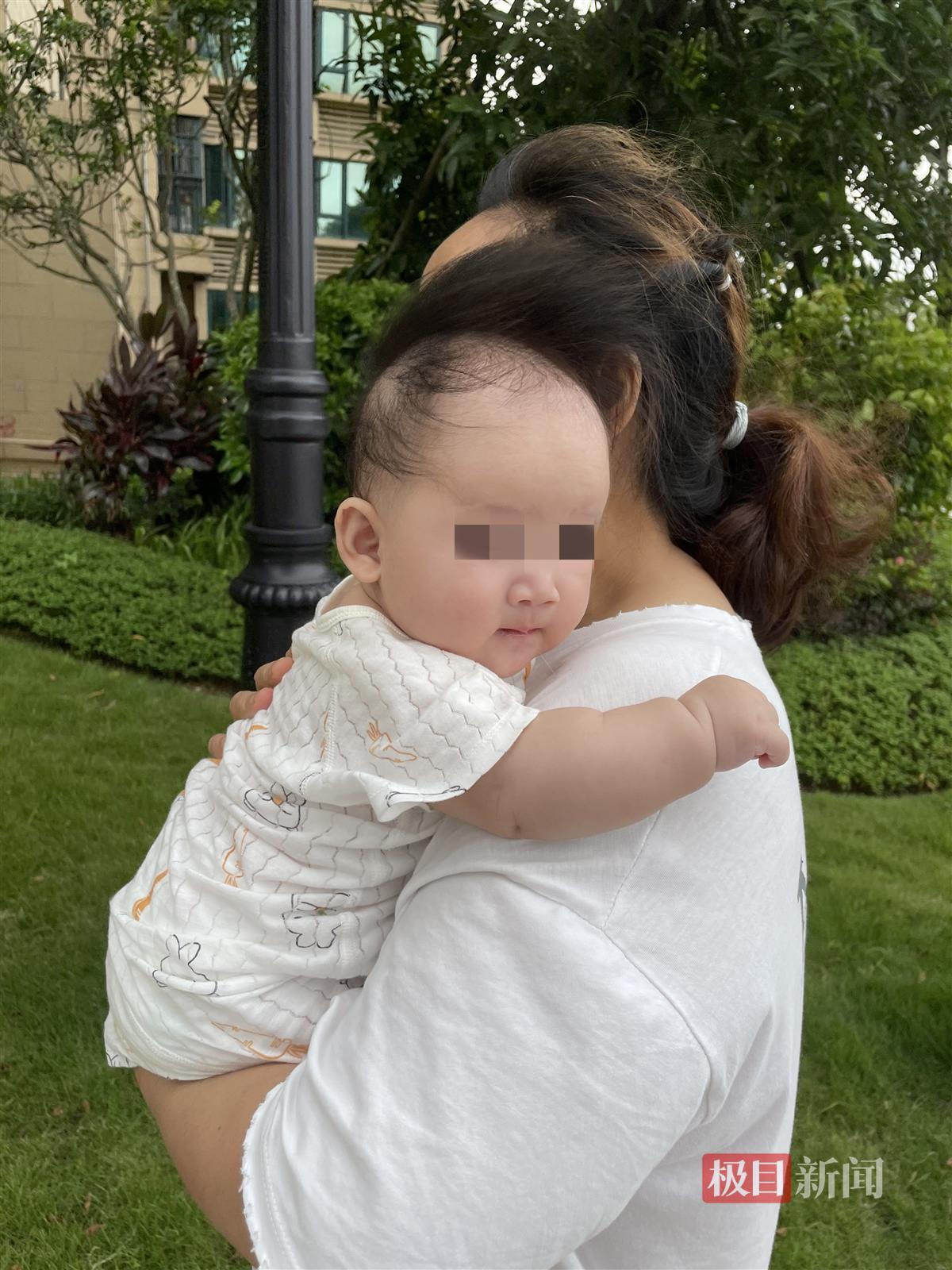 妈妈对着镜头微笑，她抱着9个月大的女婴，女婴好奇地看着她。拍摄在朴素的灰色背景照片摄影图片_ID:414412768-Veer图库