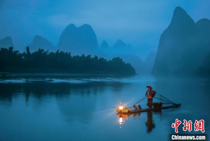 图为黄月创在展示“漓江渔火”。(资料图) 秦忠 摄