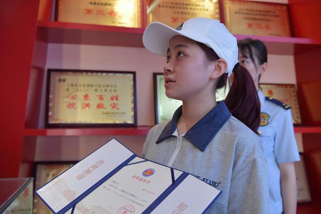 8月9日，在萍乡市上栗县消防救援大队陈列馆陶杰烈士纪念展区前，陶佳煜举着录取通知书告慰父亲。新华社记者 彭昭之 图