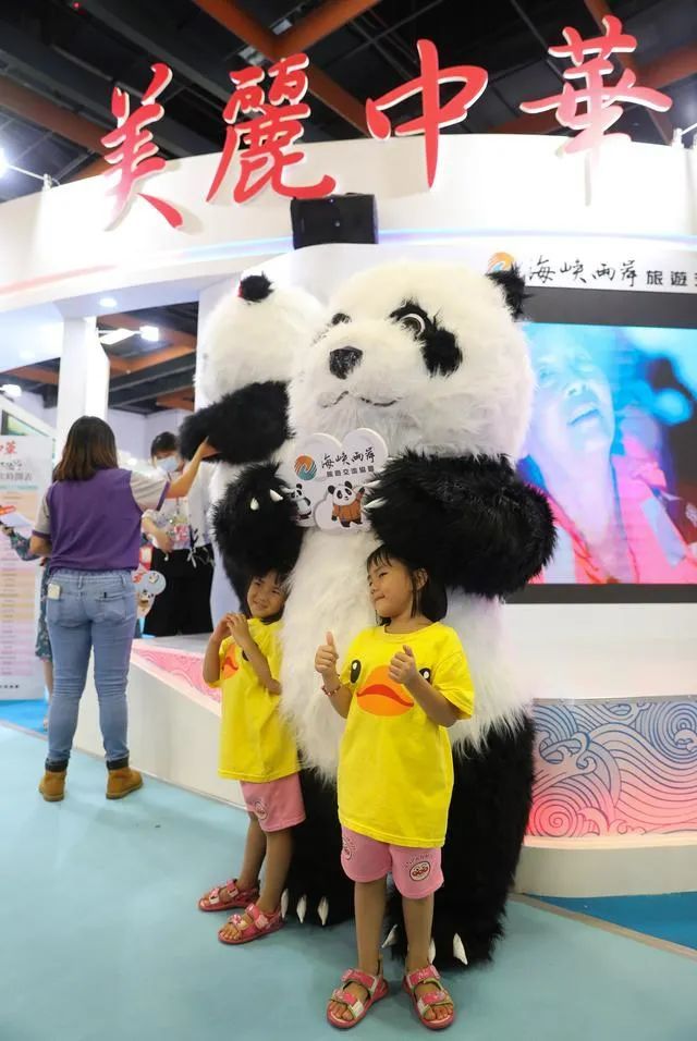 ▲2020台北夏季旅展两岸展区，小朋友和熊猫人偶合影。图/新华社