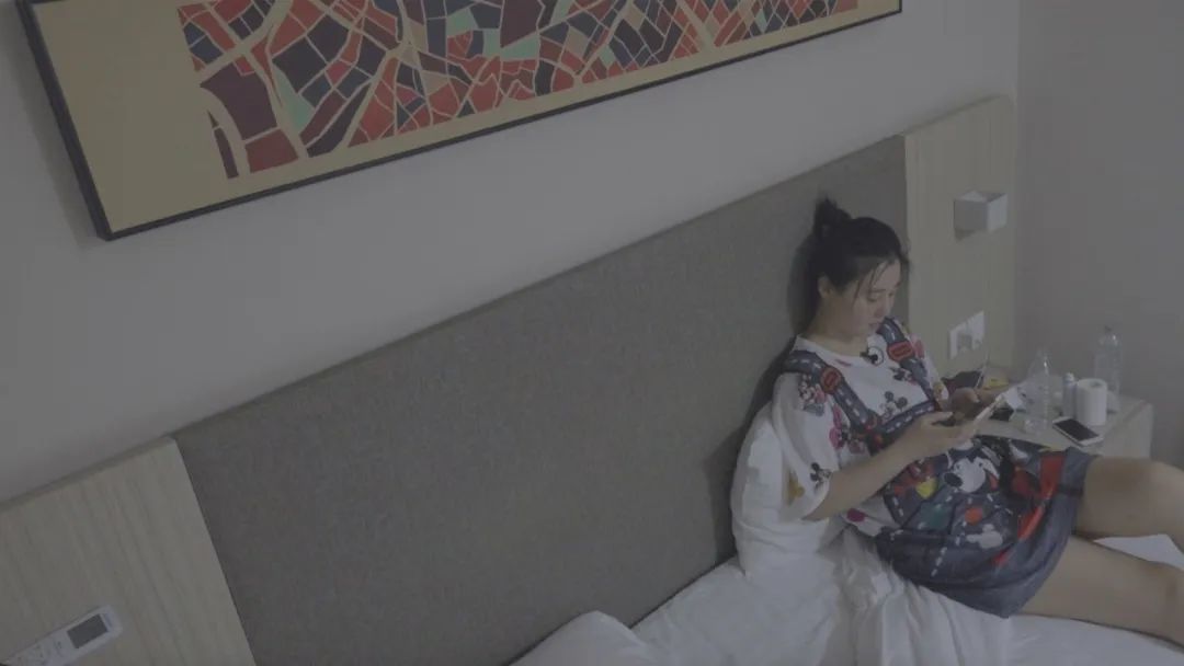 在酒店的大多时间，刘颖躺在床上玩手机。床头柜上放着两瓶酒店提供的免费矿泉水和卷纸。新京报记者 徐雪飞 摄