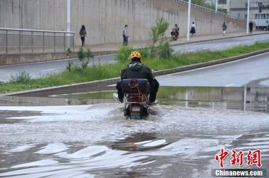 8月22日，甘肃兰州，市民驾驶电动车经过积水路段。当日凌晨，兰州遭遇持续强降雨造成部分路段积水。中新社记者 李亚龙 摄