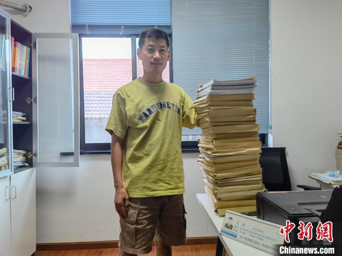办案民警王欣展示1米多高的案卷。 方云 摄