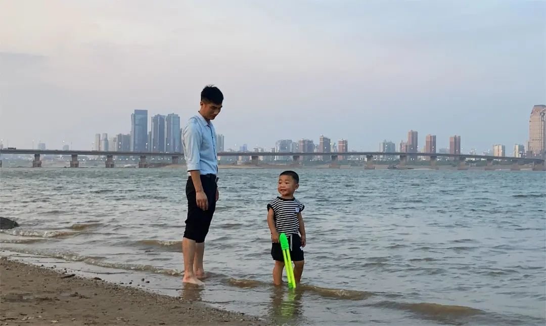 大人带着小孩在江边玩耍