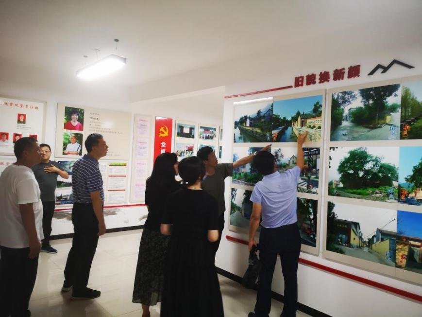 图为庙荒村村干部向大家介绍庙荒村景。