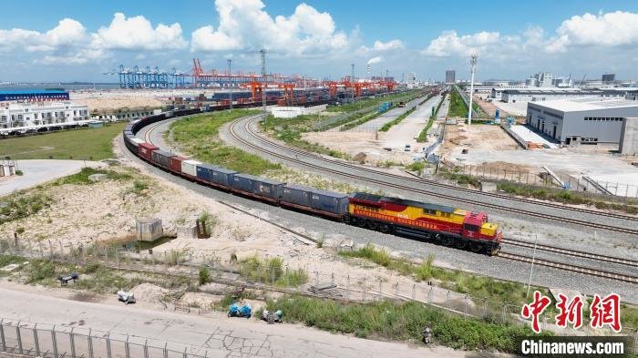 图为第20000列西部陆海新通道海铁联运班列驶离广西钦州港站。(无人机拍摄) 劳光伟 摄