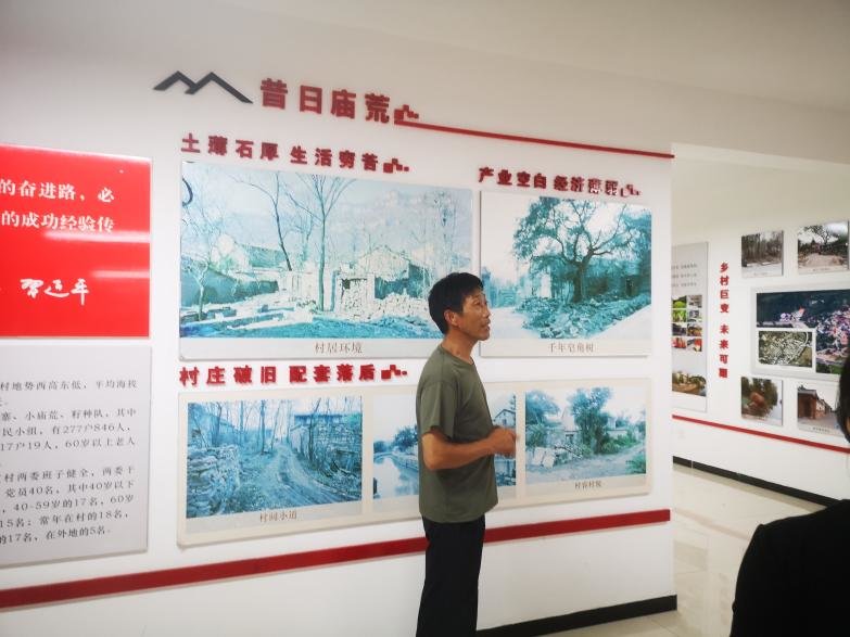 图为庙荒村村干部向大家介绍村子的脱贫之路。
