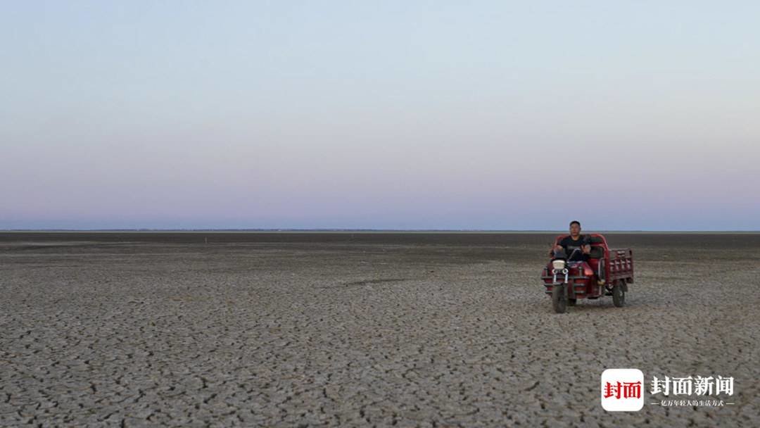 8月21日，鄱阳湖南矶山片区，村民驾驶摩托车驶入干涸的湖床。摄影：杨峰