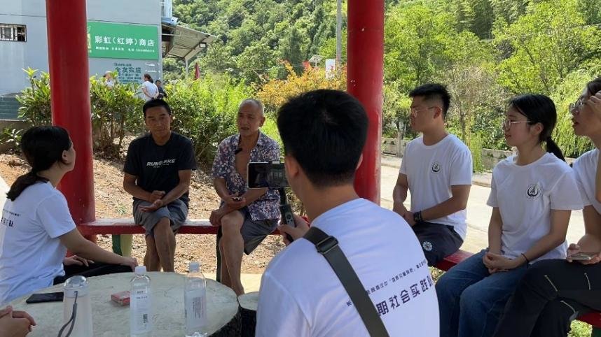 图为实践队员与当地村民范孝财（左）、何兴华（右）了解扶贫攻坚等实况。（王梓怡 摄）