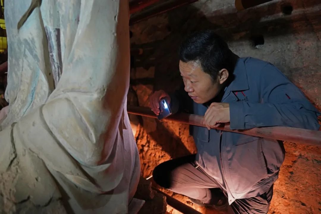 2022年8月17日，负责考古的麦积山石窟艺术研究所副所长张铭，正在辨识佛像背后发现的不同朝代的题记。新京报记者陈杰 摄