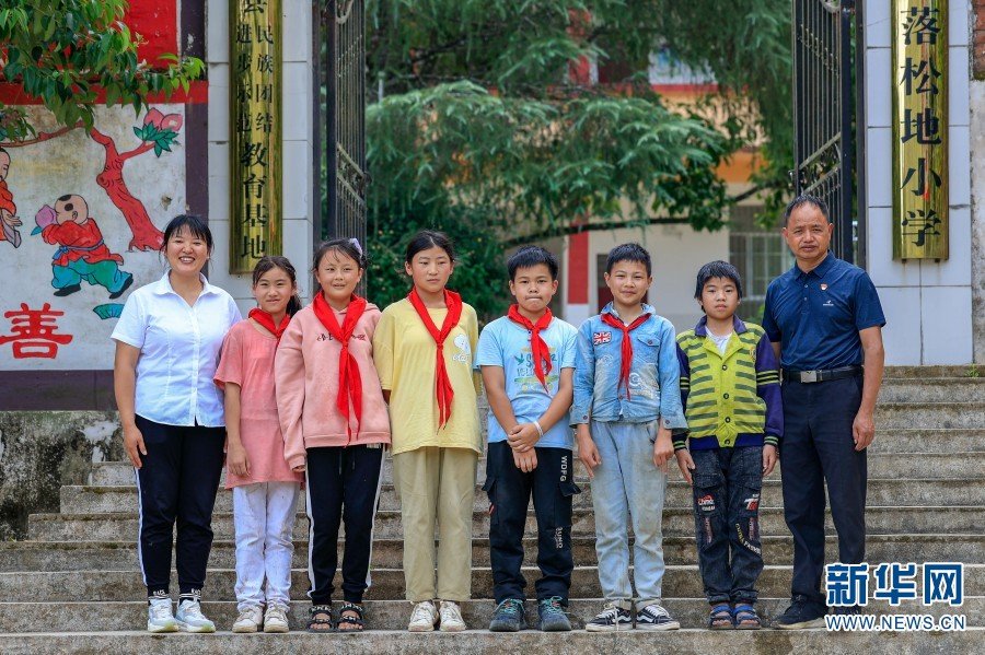 2022年7月6日,落松地小学的6名毕业生和农加贵老师、朱丽丹老师在校门口留影。(新华网 赵普凡 摄)