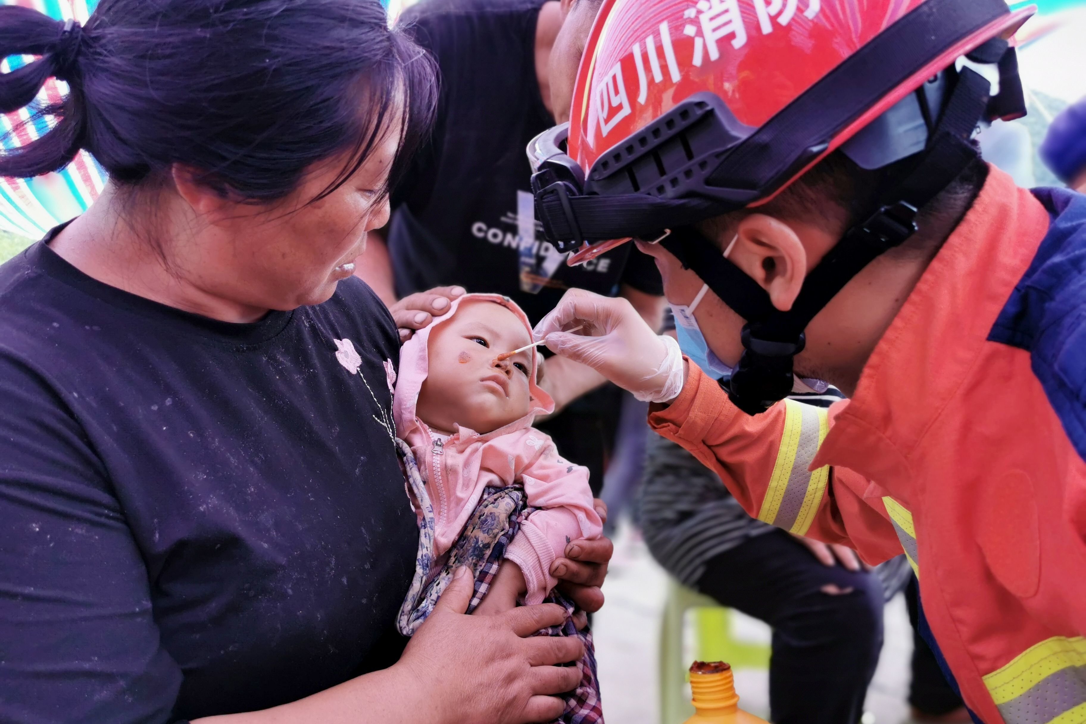 四川消防及当地医护人员组成的前突分队，在王岗坪乡幸福村为一名在地震中擦伤的幼儿用碘伏擦拭伤口。受访者供图