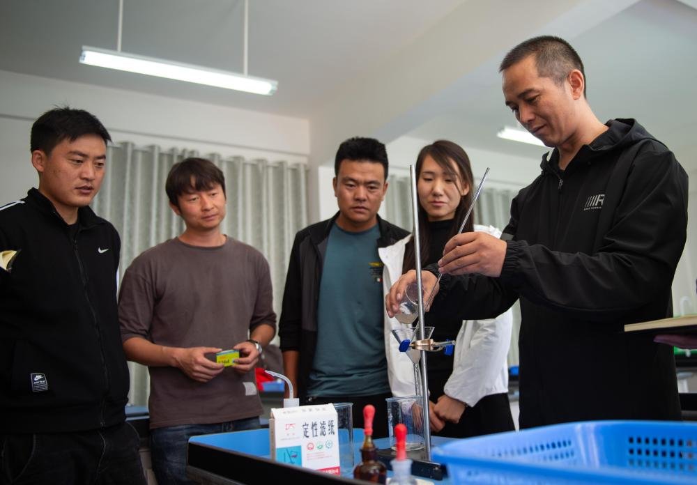 北京市援青支教教师、来自通州区陆辛庄学校的化学教师祁生贵（右一）在青海省玉树州第四民族高级中学指导学校教师进行实验教学（2020年8月12日摄）。新华社记者 陈钟昊 摄