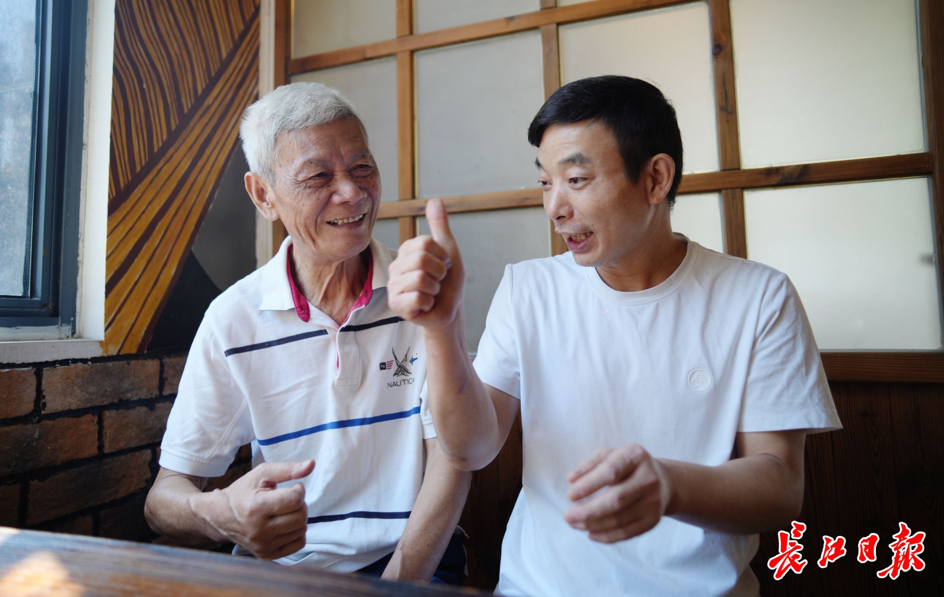 桂玉财（左）到店中看望李志成。 记者何晓刚 摄