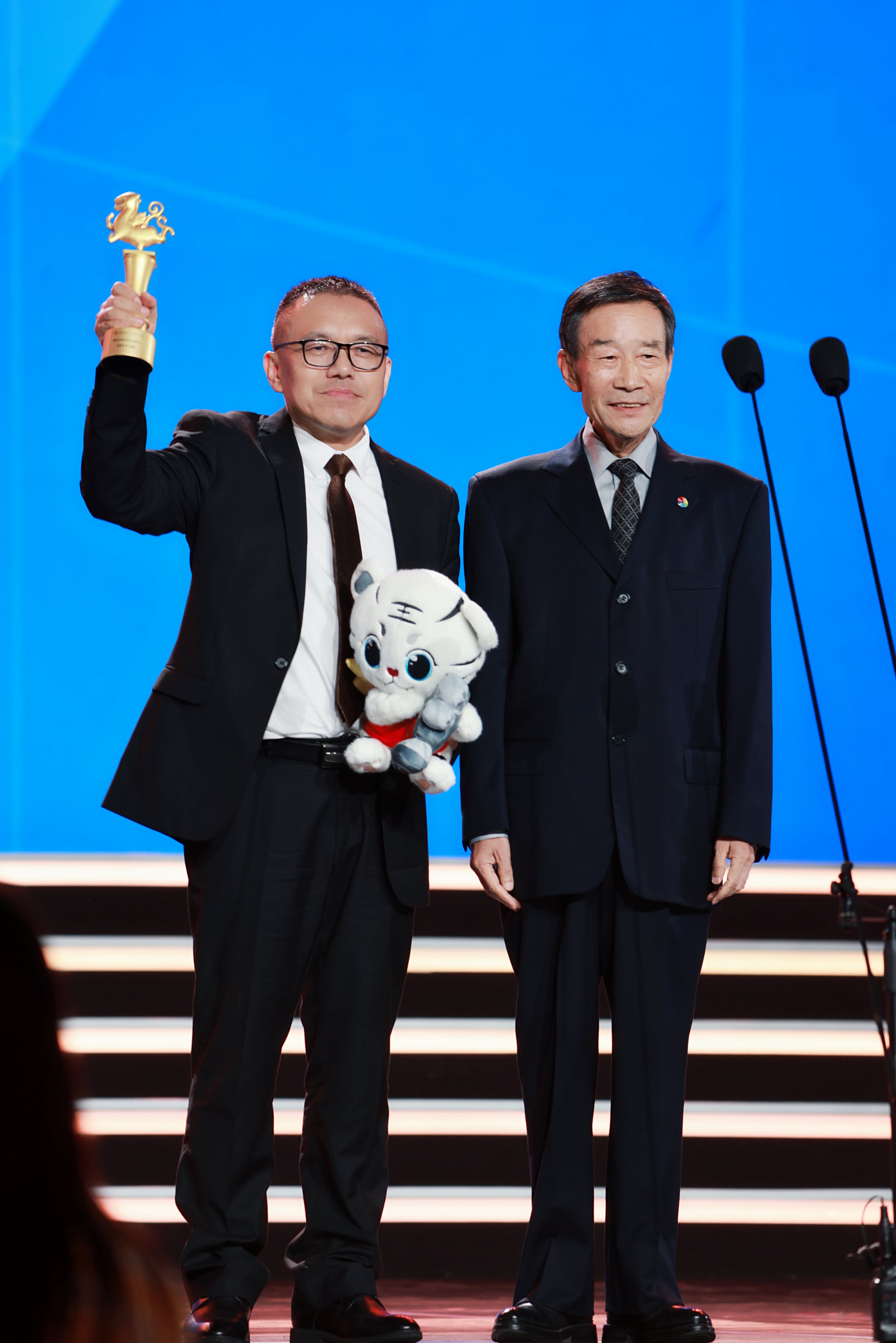 闻名扮演艺术家李雪健(右一)向出品人/制片人黄平(左一)发表声誉