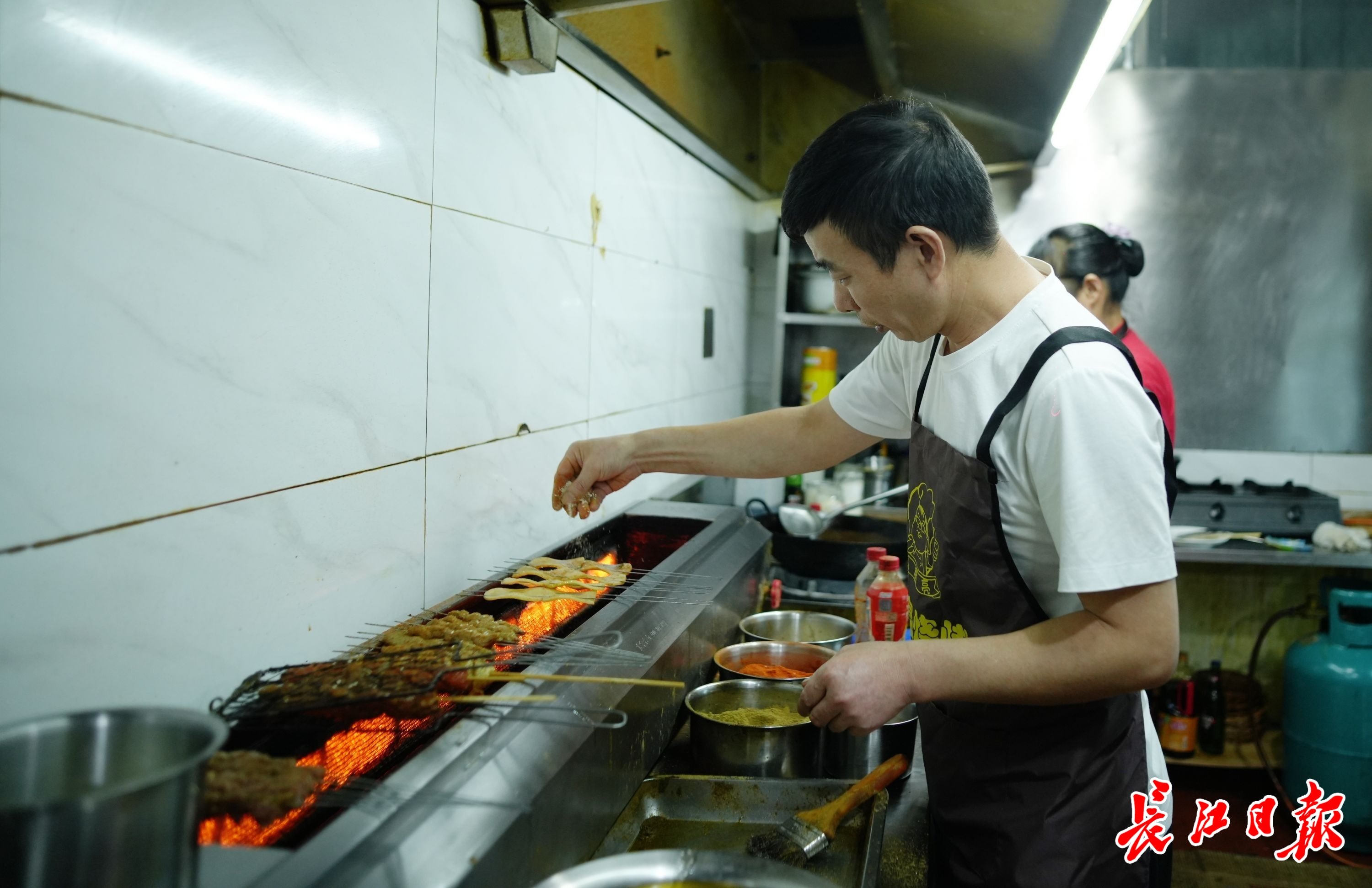 李志成在烤肉串。 记者何晓刚 摄