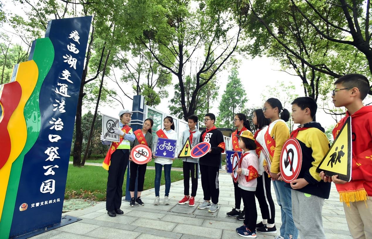 在扬州，旅游警察在“口袋公园”给小志愿者讲解交通标志牌。图/庄文斌