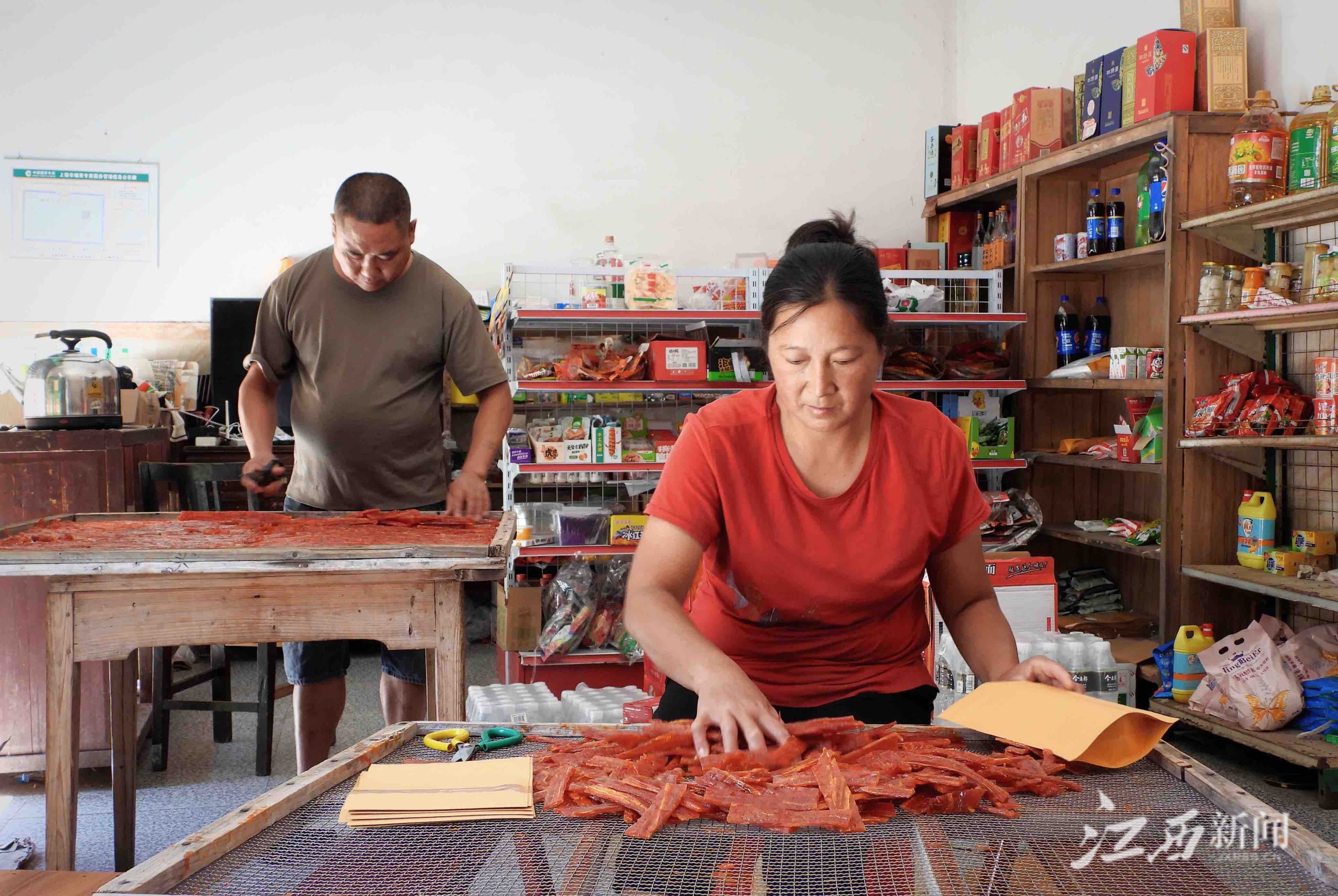 ▲村民洪鲜花（前）负责包装，她的老公董有则负责将晒好的南瓜果剪成小块。