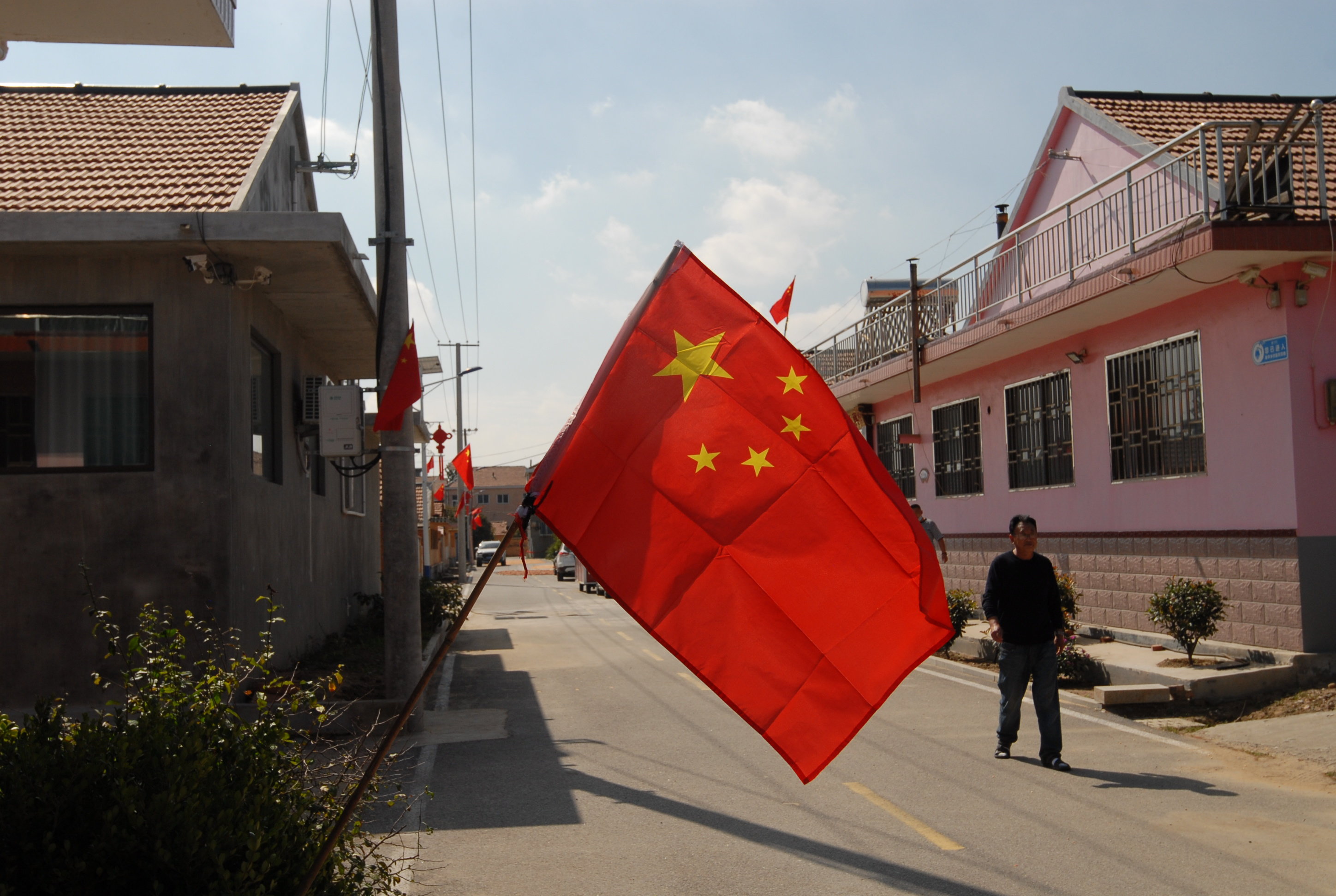 9月30日，一位村民在家门口悬挂的国旗前走过。