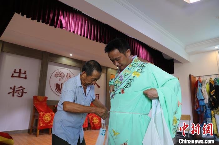 图为彭泽高腔剧团演员在表演前穿上戏服。　袁昕 摄