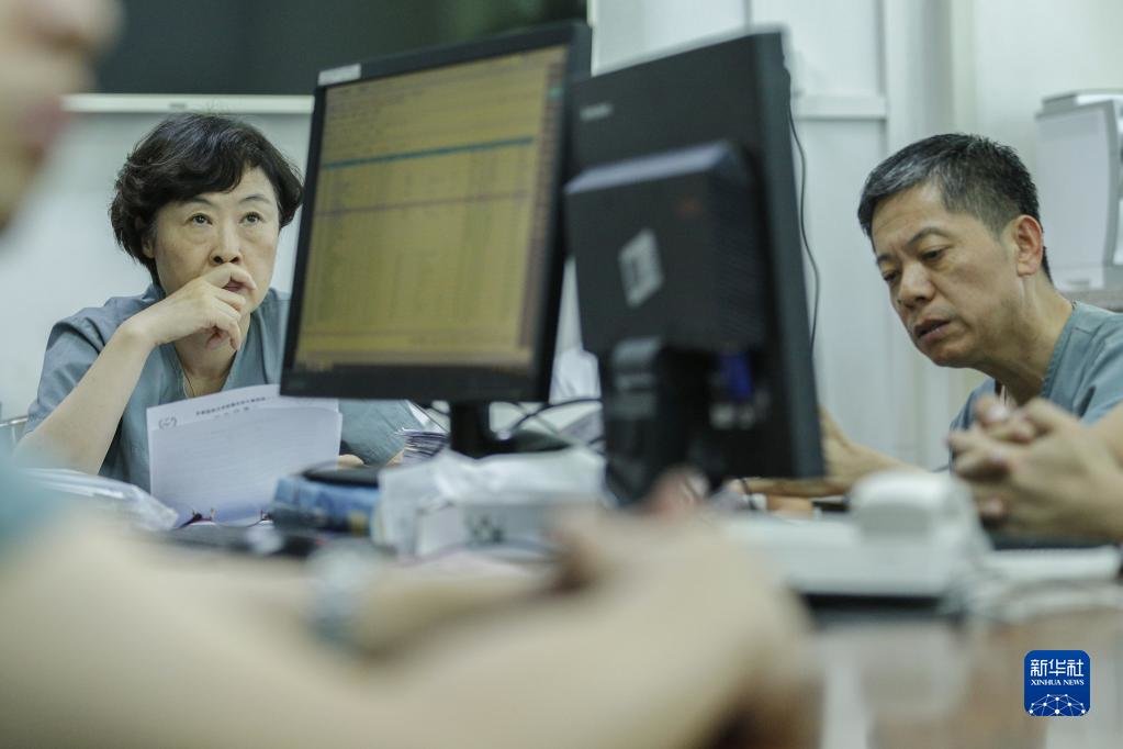钱素云（左）在办公室参加病例讨论（2019年7月31日摄）。新华社记者 才扬 摄