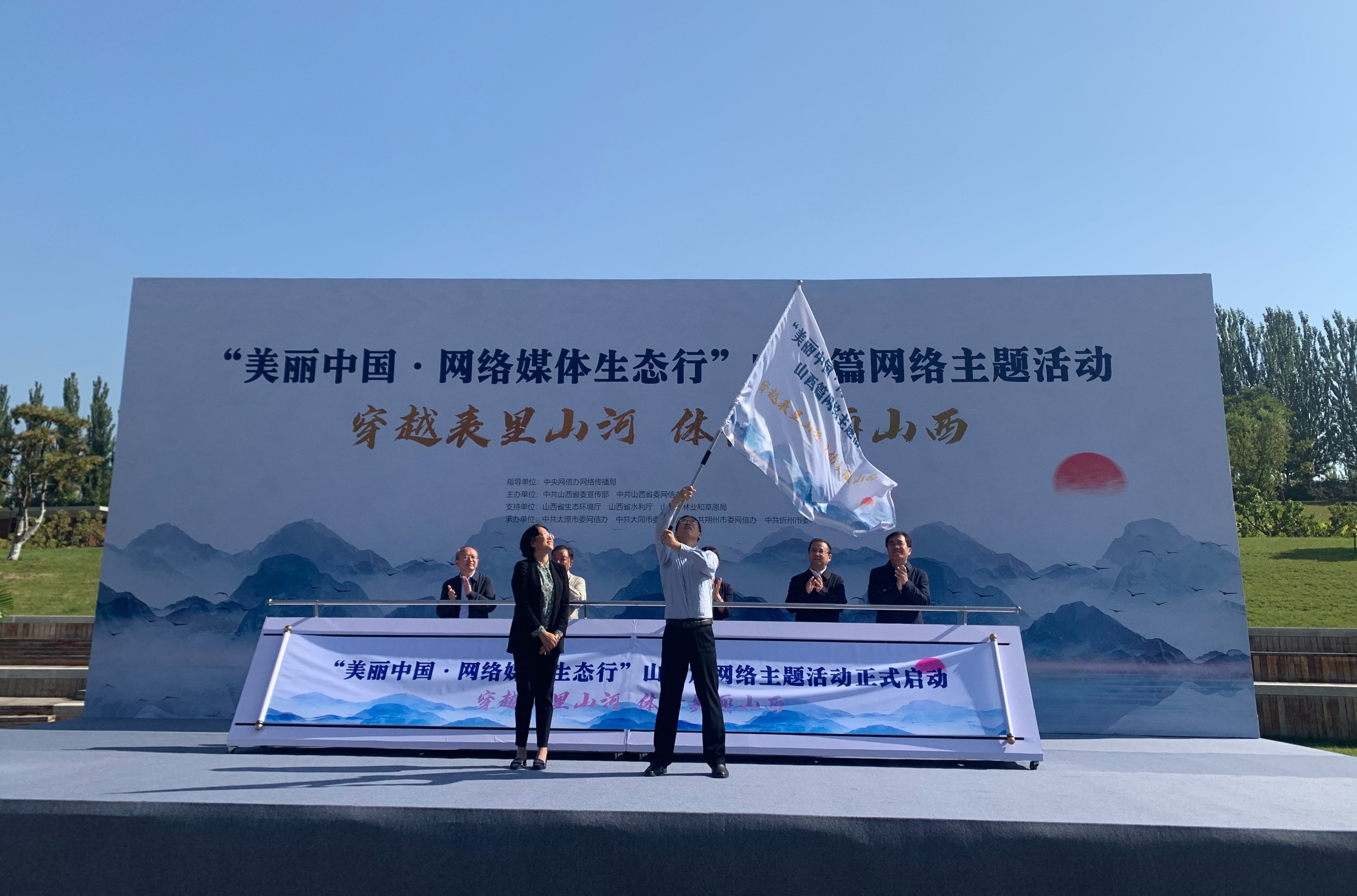 图为贾彩香为采访团授旗