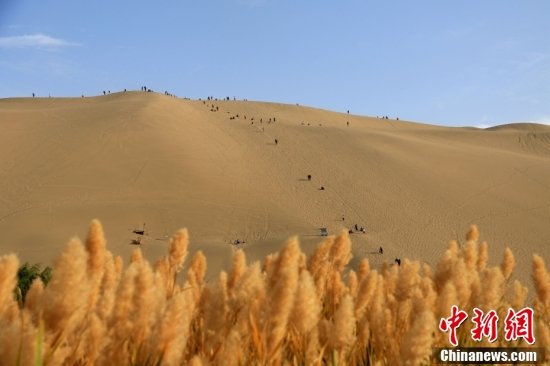 游客在甘肃省敦煌市鸣沙山月牙泉景区游览