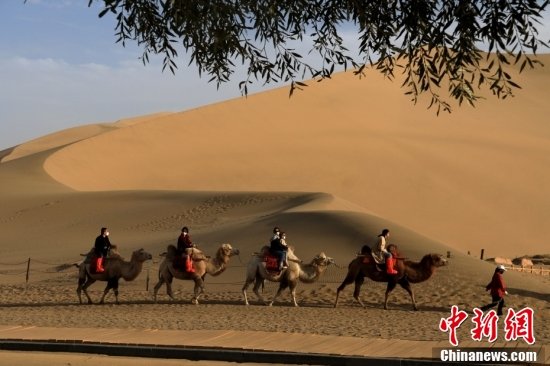 游客在甘肃省敦煌市鸣沙山月牙泉景区游览