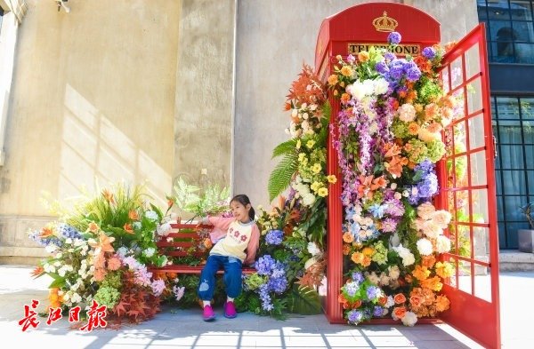 小朋友在青岛路上满是花朵的电话亭拍照。 记者许魏巍 摄
