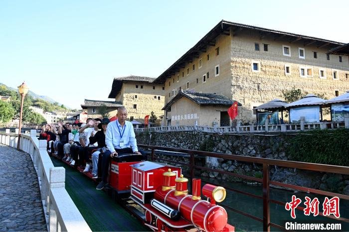 游客坐小火车游览南江村土楼。　张金川 摄