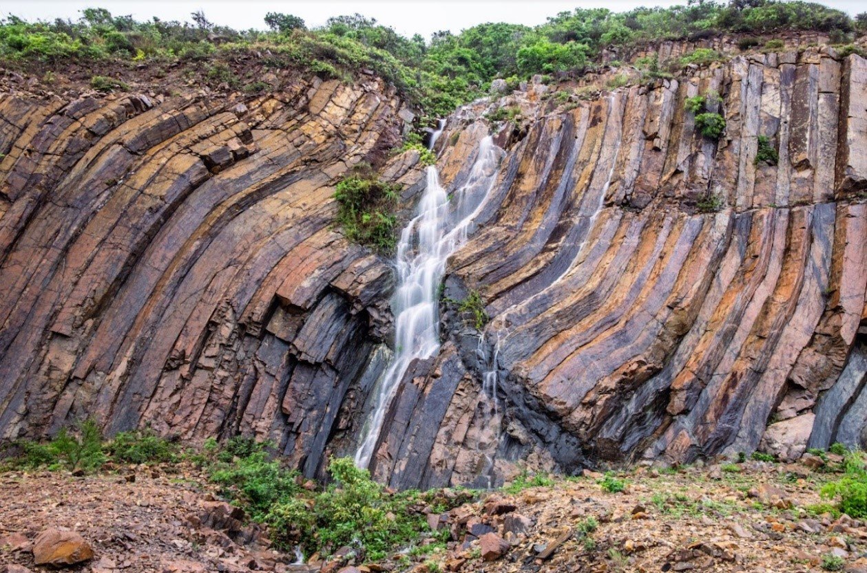 香港万宜水库东坝， 受地质运动影响弯曲变形的岩柱，中间还有一道后期侵入的玄武岩质岩墙。