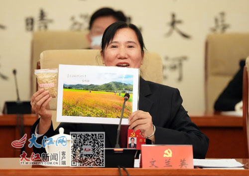 文兰英代表在讨论会上展示水稻种子和家乡良种繁育基地的照片。