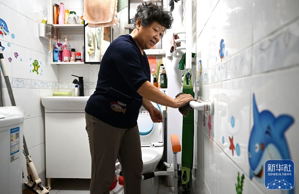 ↑ 在天津市和平区文化村社区一居民家中，老人在擦拭卫生间内安装的防滑助力扶手（10月27日摄）。