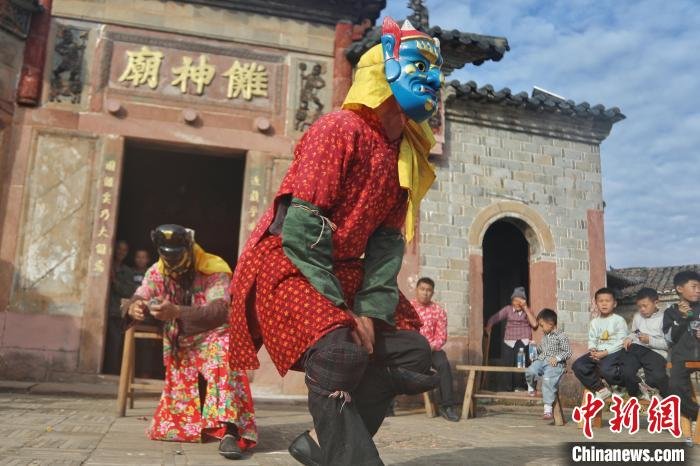 图为身着傩服的演员正在表演，不少游客和村民在一旁观看。　刘力鑫 摄