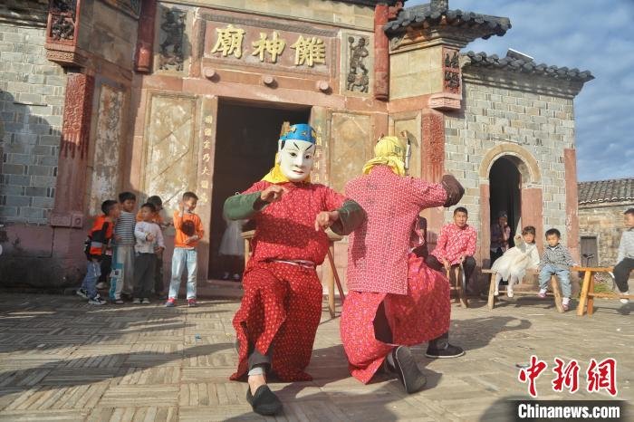 图为身着傩服的演员正在表演，不少游客和村民在一旁观看。　刘力鑫 摄