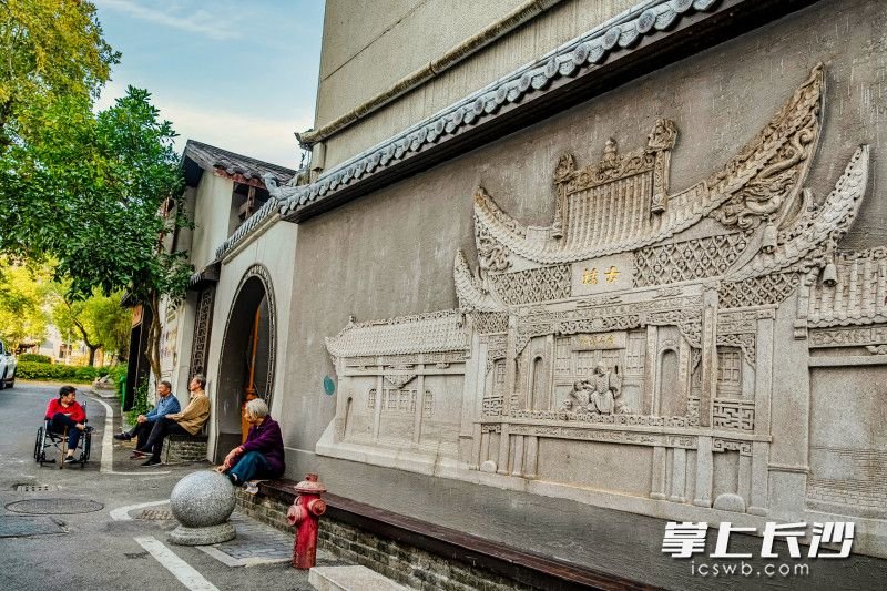 青山祠街古戏台浮雕墙生动而精致，老人们在路边在悠闲的聊天。均为全媒体记者 陈飞 摄