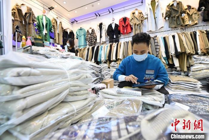 图为永定城·京津冀(固安)国际商贸城的商户正在对服装清点打包，通过快递物流送到顾客手中。　刘向 摄