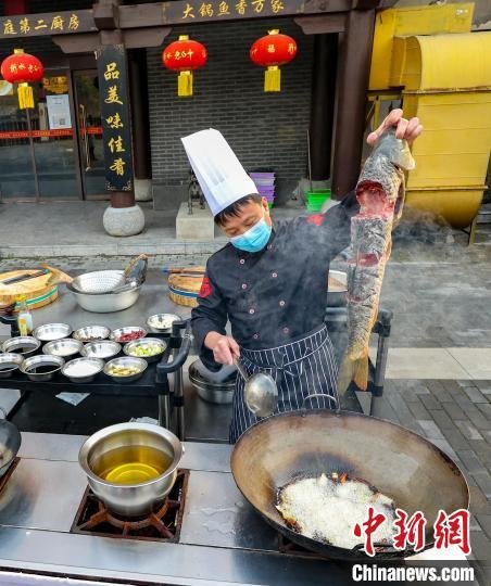 招牌菜铁锅炖大鱼下锅烹饪。 王耀 摄