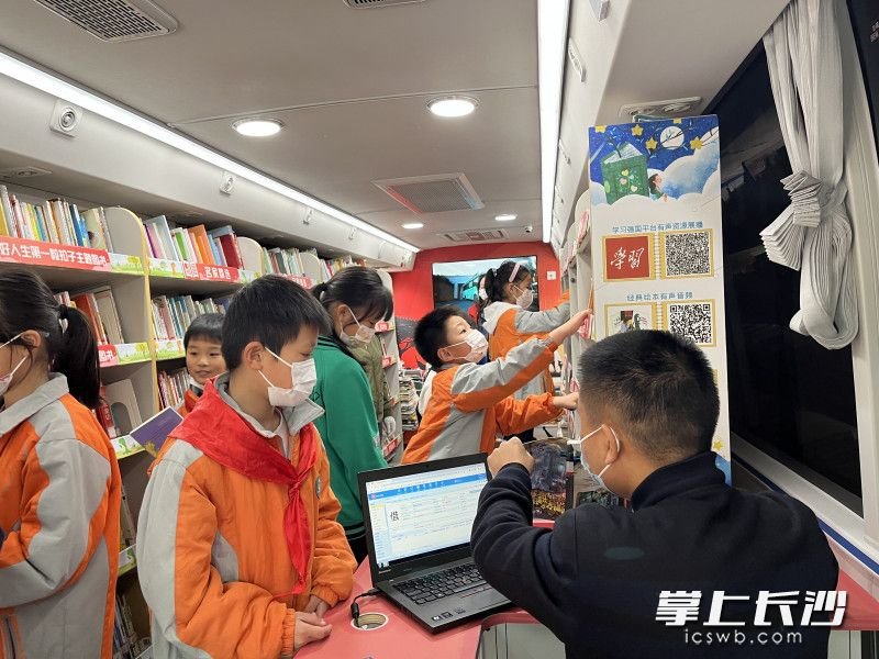 孩子们在流动图书馆上纷纷挑选自己感兴趣的书籍。