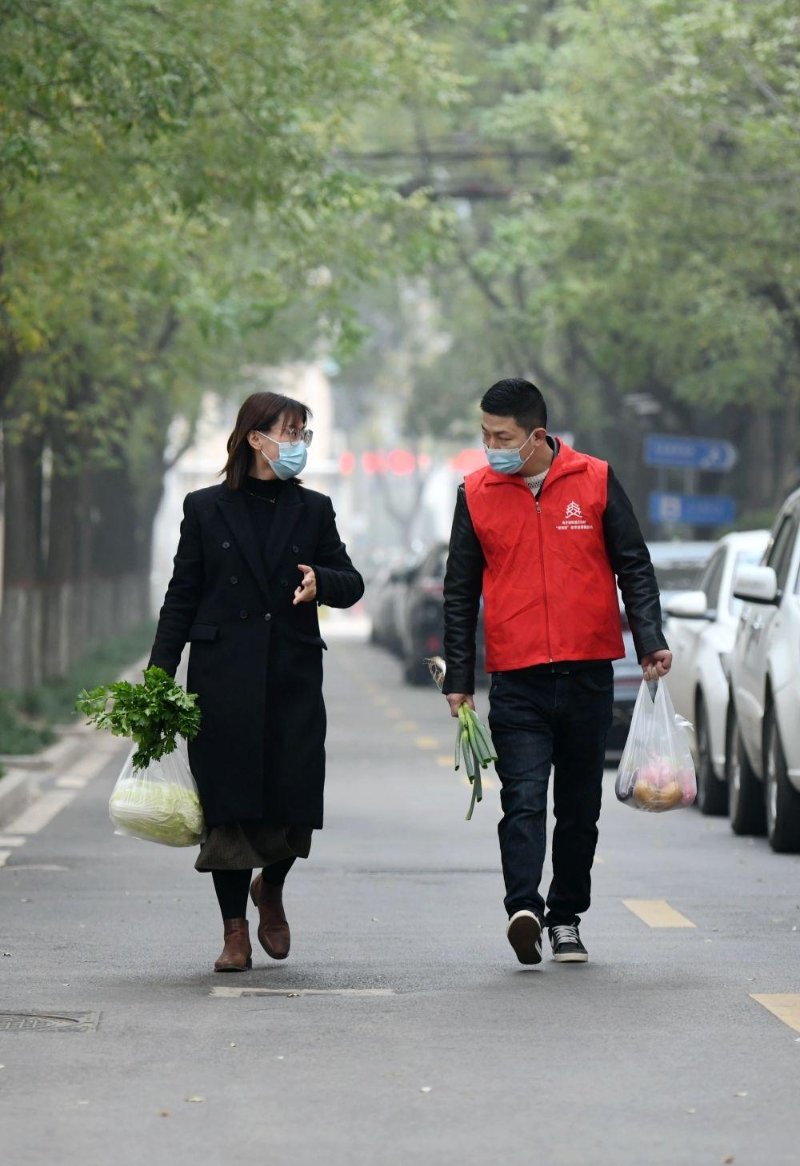 11月17日，西安市雁塔区电子城街道二〇五所社区党支部书记于珍（左）和志愿者薛亚洲带着蔬菜上门探望社区老人。新华社记者 李一博 摄