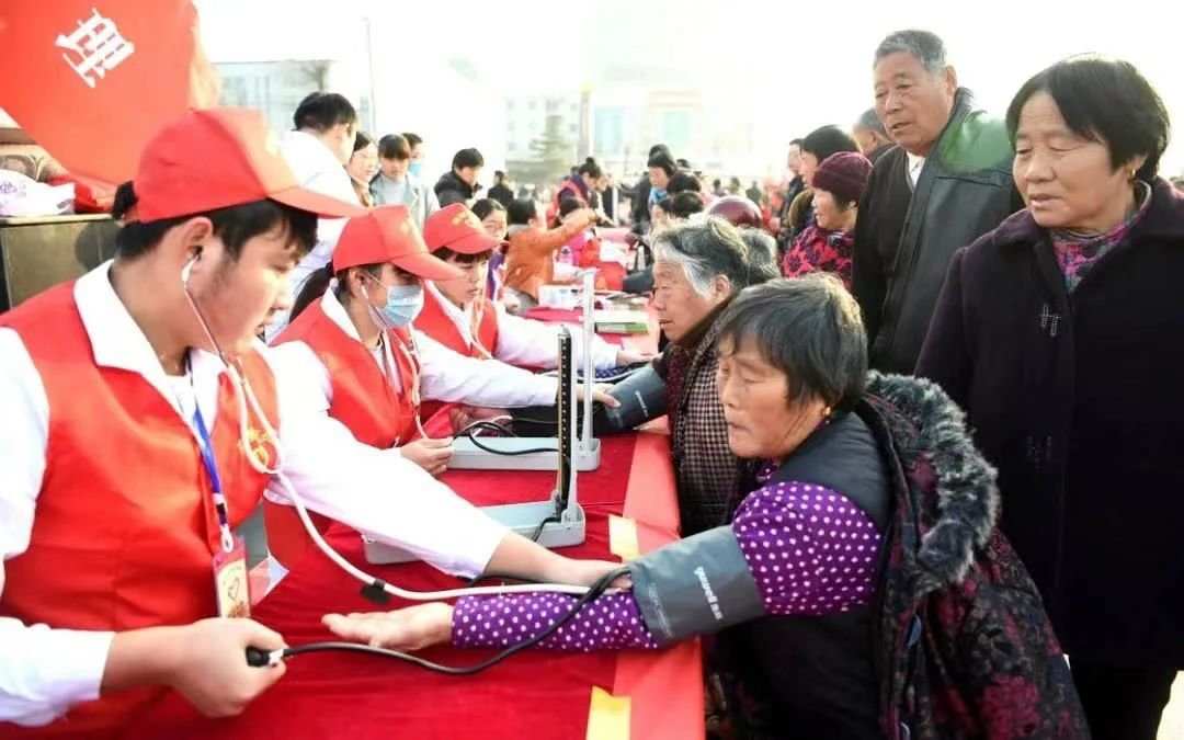 志愿者在安徽亳州市魏武广场为市民义务测量血压。图片来源：新华社