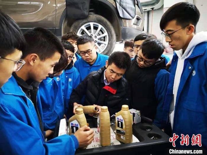 图为2020年11月，孙怀君(中间黑衣者)带领学生为社区居民免费维护汽车。(资料图)　兰州石化职业技术大学供图