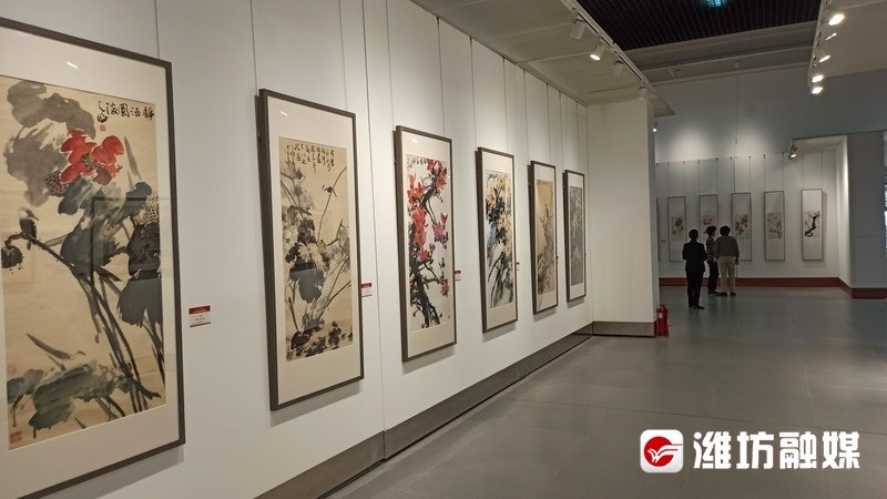 几名书画爱好者在中国青州书画年会参观书画作品。