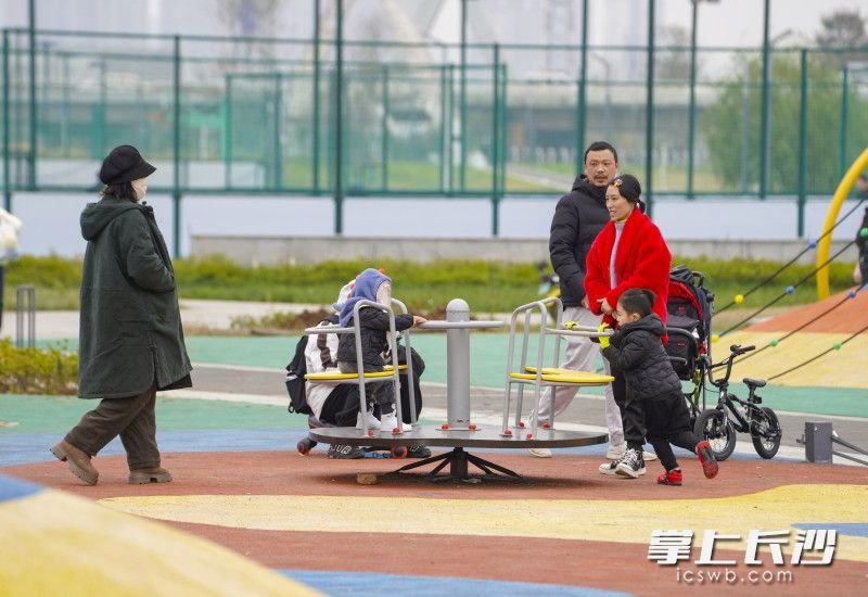 在家长陪伴下，孩子们玩转着公园内的旋转台。