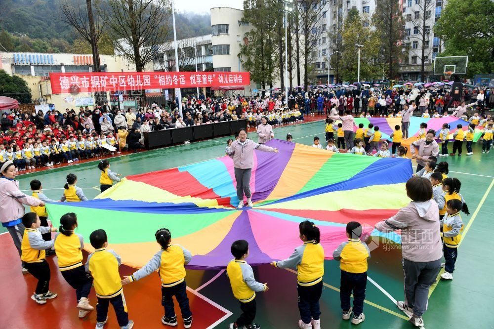 2022年12月8日，江西省德兴市铜矿中区幼儿园小朋友正在进行彩虹伞表演，吸引众多群众前来观看。
