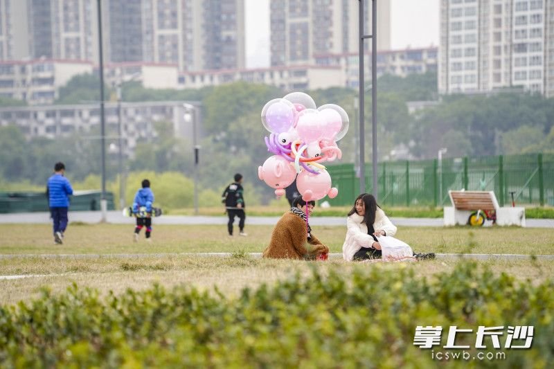 两位女士在草地上铺上毯子，盘腿而坐，神情愉悦。