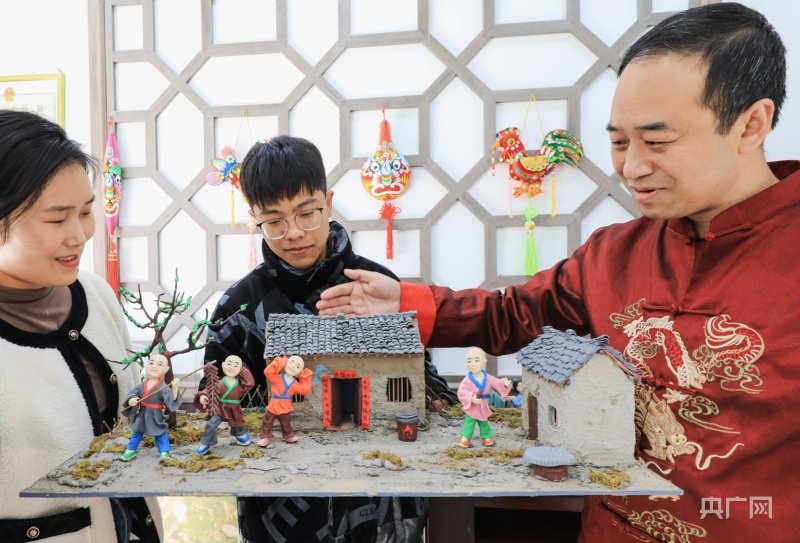 安秋平向游客介绍面塑作品《过大年》（央广网发 吴庭栋 摄）