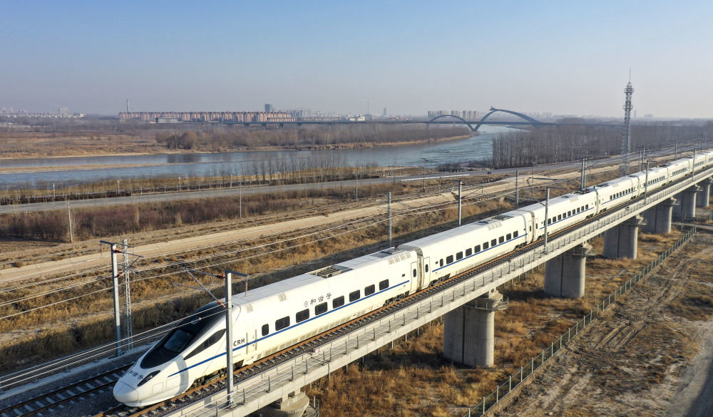 12月29日，在宁夏中卫市境内，行驶在银兰高铁上的D2763次列车从黄河旁经过（无人机照片）。新华社记者 冯开华 摄