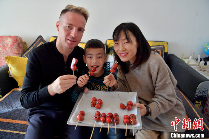 图为长春市民金辉（右）和儿子、丈夫在家中展示她制作的冰糖葫芦。 中新社记者 张瑶 摄